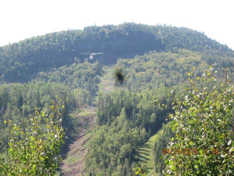 A helicopter delivers one of the gondola standards to the construction site