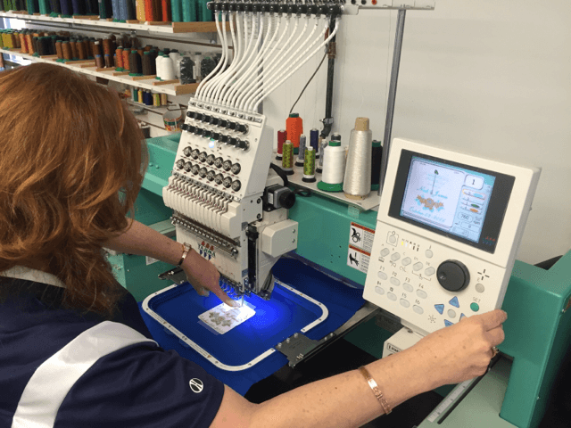 Jean Edin checks the thread colors on the computer control before beginning a jacket embroidery project.